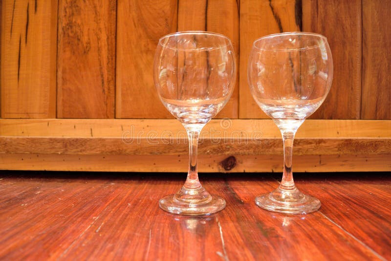 a photo of two empty wine glasses on a wooden background. a photo of two empty wine glasses on a wooden background