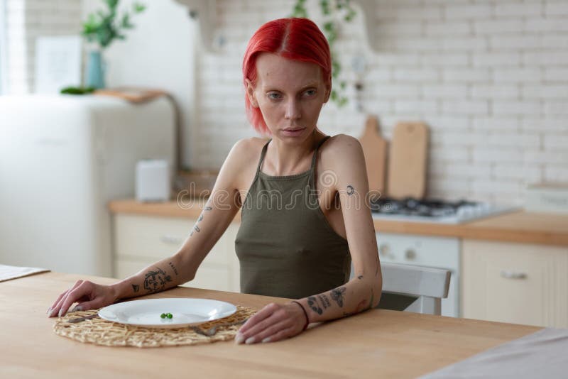 Больная анорексией женщина имея ужасное усаживание взгляда в кухне стоковые изображения rf