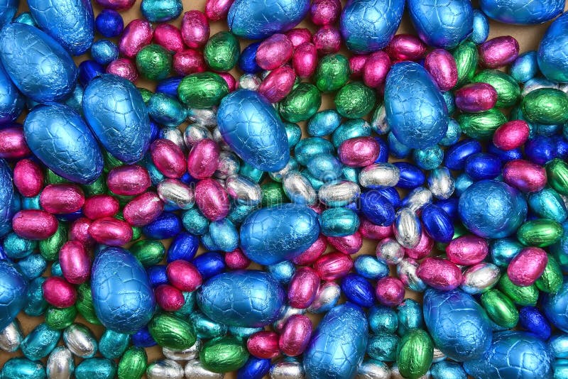 большие&маленькие розовые зеленые и серебряные яйца с шоколадными пасхальными корнями на бледном фоне. стоковое изображение
