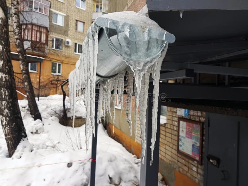 Большие опасные сосульки над входом к дому в зиме или весной против снега стоковое фото