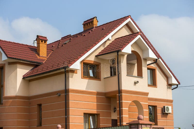 Большие современные дорогие роскошные жилые 2-рассказы коттедж, дом семьи с постриженной коричневой крышей, высокими каминами кир стоковые изображения rf Большие современные дорогие роскошные жилые 2-рассказы коттедж, дом семьи с постриженной коричневой крышей, высокими каминами кир стоковые изображения rf