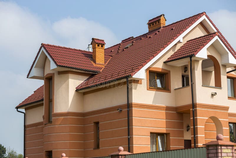 Большие современные дорогие роскошные жилые 2-рассказы коттедж, дом семьи с постриженной коричневой крышей, высокими каминами кир стоковое изображение rf Большие современные дорогие роскошные жилые 2-рассказы коттедж, дом семьи с постриженной коричневой крышей, высокими каминами кир стоковое изображение rf