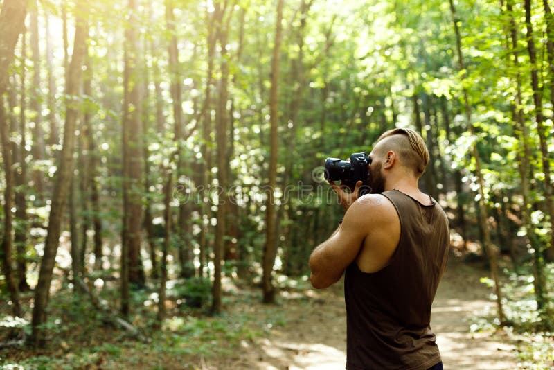 Бородатый человек фотографа trekking среди леса и фотографируя с камерой dslr Горизонтальная форма, космос экземпляра стоковые фотографии rf Бородатый человек фотографа trekking среди леса и фотографируя с камерой dslr Горизонтальная форма, космос экземпляра стоковые фотографии rf