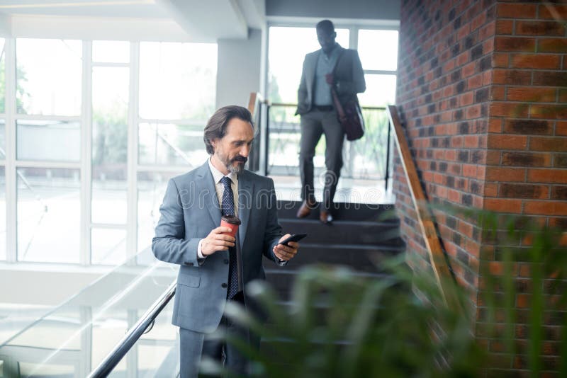 Бородатое седое сообщение чтения работника офиса в смартфоне стоковые фото