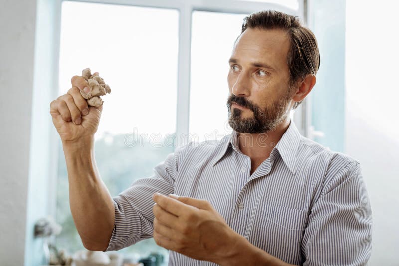 Бородатое темн-с волосами воодушевленное чувство человека пока делающ вазу глины стоковое фото rf