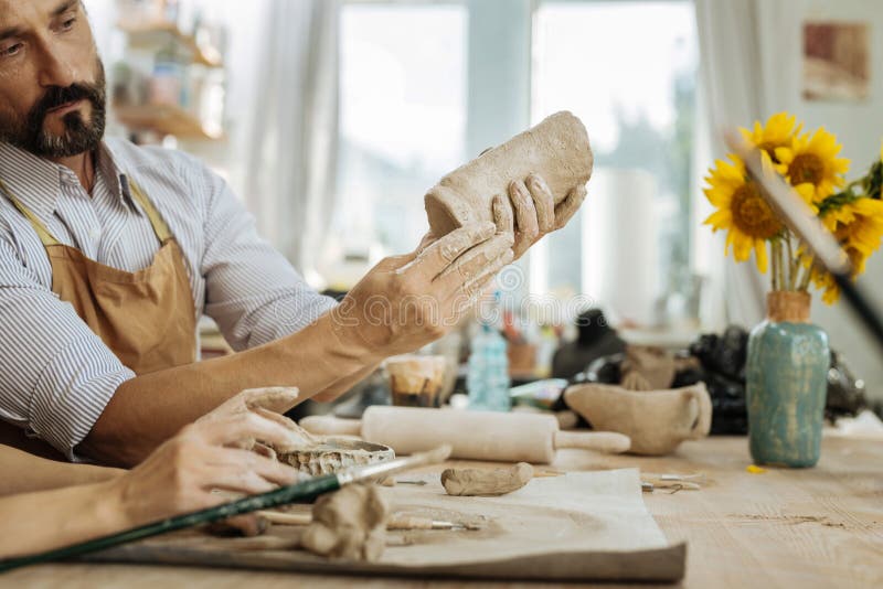 Бородатое темн-с волосами занятое чувство гончара делающ вазу стоковые фотографии rf