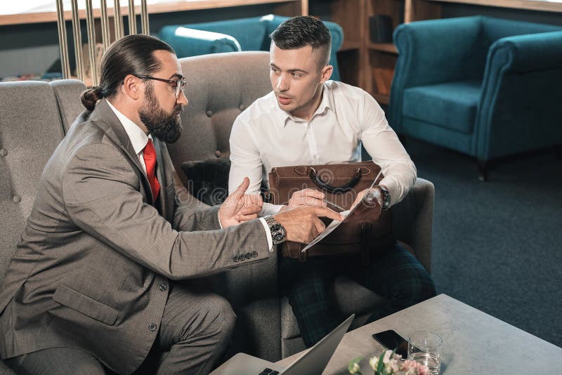 Бородатый темн-с волосами деловой партнер давая его мнение на ситуации стоковое изображение rf