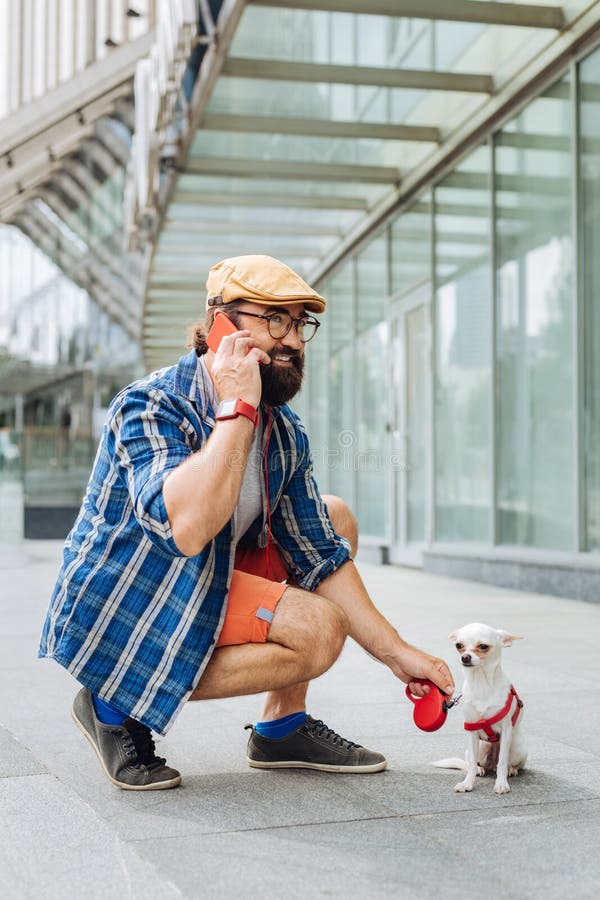 Бородатый темн-с волосами человек говоря на телефоне пока идущ стоковые фото