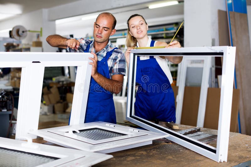 Portrait adult brigade of two people working at workshop for production of plastic windows. Portrait adult brigade of two people working at workshop for production of plastic windows