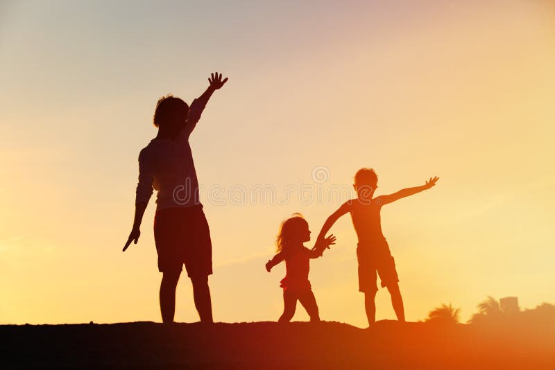 Father with son and daughter silhouettes play at sunset sky. Father with son and daughter silhouettes play at sunset sky