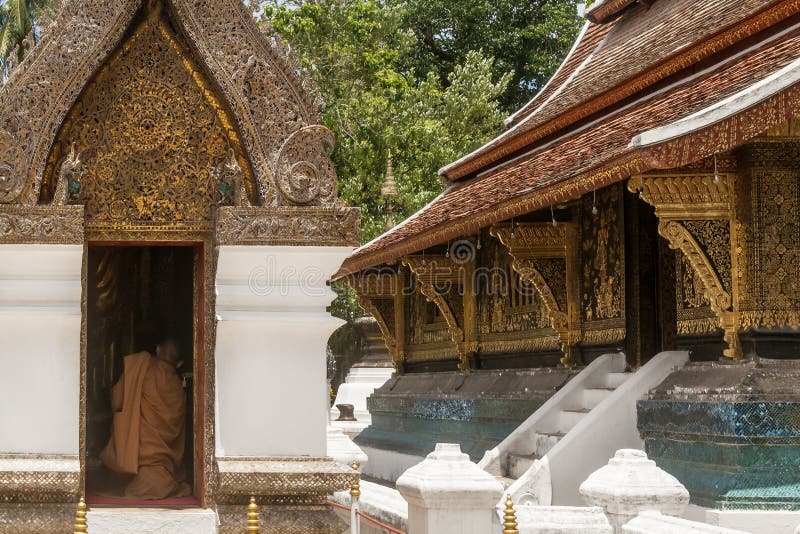 Буддийский монах молит вставать в святыне внутри виска ремня Wat Xieng в Luang Prabang, Лаосе стоковые изображения rf Буддийский монах молит вставать в святыне внутри виска ремня Wat Xieng в Luang Prabang, Лаосе стоковые изображения rf