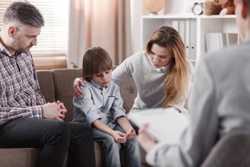 Mother hugging her autistic son, sitting next to his father during family therapy. Mother hugging her autistic son, sitting next to his father during family therapy