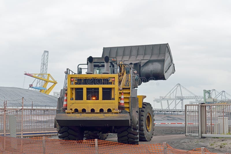 Yellow bulldozer on coal plant in the port of rotterdam netherlands. Yellow bulldozer on coal plant in the port of rotterdam netherlands