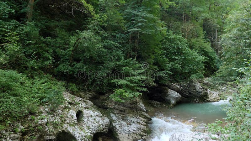 быстрая горная река в горном ущелье, вода течет над большими камнями.