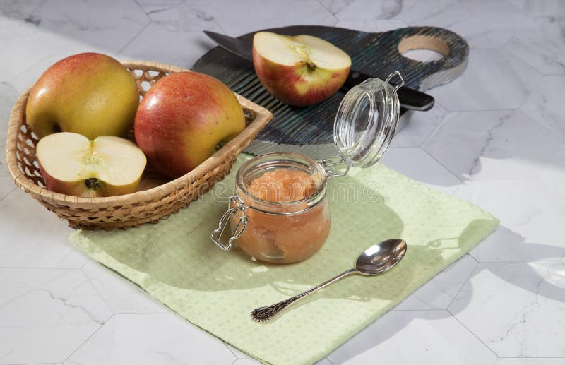 В отличии от яблони и applesauce плетеной тарелке на светлом фоне отрезанное apple на деревянной разделочной доске. стоковое фото