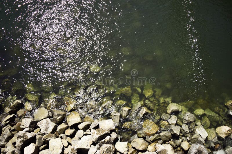 В результате снимок камней на дне и вокруг пруда воды стоковое изображение