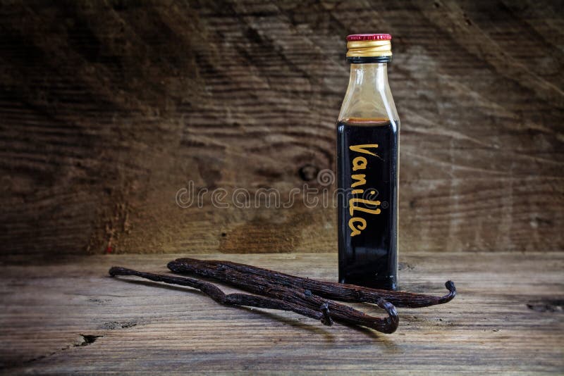 Vanilla extract, homemade in a small bottle and vanilla beans on a rustic wooden background. Vanilla extract, homemade in a small bottle and vanilla beans on a rustic wooden background
