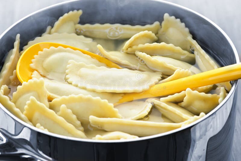 Cooking and stirring pot of ravioli pasta in boiling water. Cooking and stirring pot of ravioli pasta in boiling water