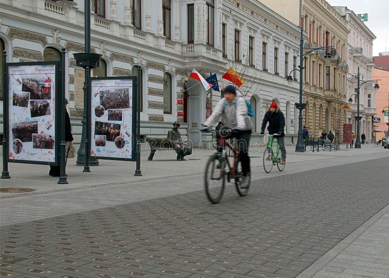 Cyclists on the background of the monument Tuwim bench on Piotrkowska Street in Lodz. Cyclists on the background of the monument Tuwim bench on Piotrkowska Street in Lodz.