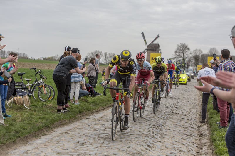Templeuve, France - April 08, 2018: The German cyclist Tony Martin of Team Katusha-Alpecin riding in the peloton on the cobblestone road in Templeuve in front of the traditional Vertain Windmill during Paris-Roubaix 2018. Templeuve, France - April 08, 2018: The German cyclist Tony Martin of Team Katusha-Alpecin riding in the peloton on the cobblestone road in Templeuve in front of the traditional Vertain Windmill during Paris-Roubaix 2018.