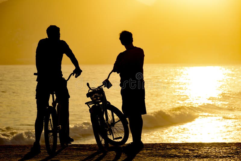 Two cyclists during the late afternoon on the seafront watching the sunset. Two cyclists during the late afternoon on the seafront watching the sunset