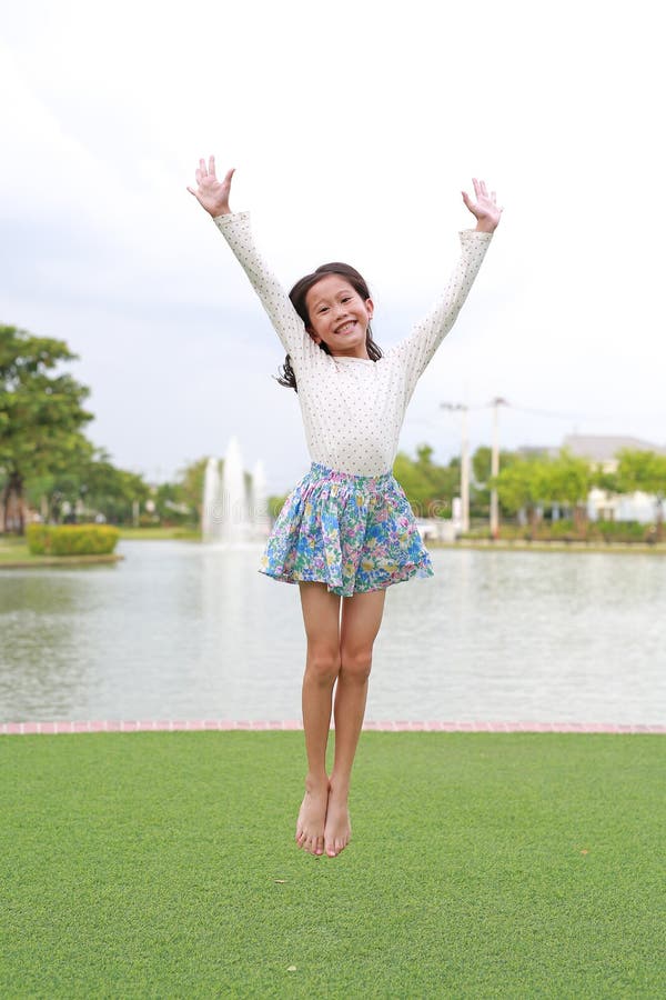 веселая азиатская девочка прыгает в саду стоковые фотографии rf