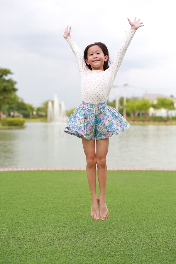 веселая азиатская девочка прыгает в саду стоковые изображения rf