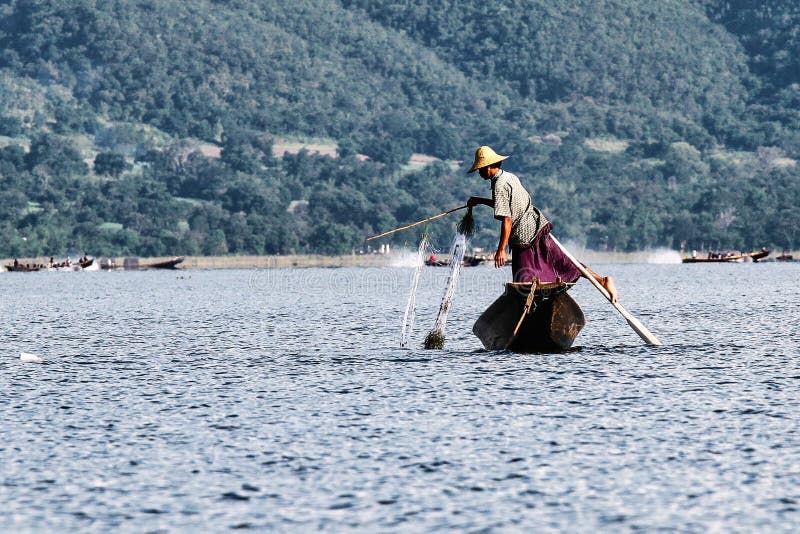 Весельная лодка рыболова ногой на озере Inle, Мьянме стоковое фото rf Весельная лодка рыболова ногой на озере Inle, Мьянме стоковое фото rf
