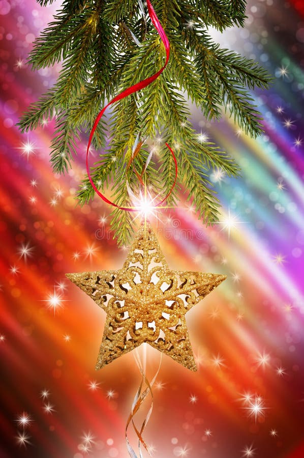 A pine branch from a Christmas tree with a golden star hanging downward. The background is a brightly colored blur with stars and dots. A pine branch from a Christmas tree with a golden star hanging downward. The background is a brightly colored blur with stars and dots.