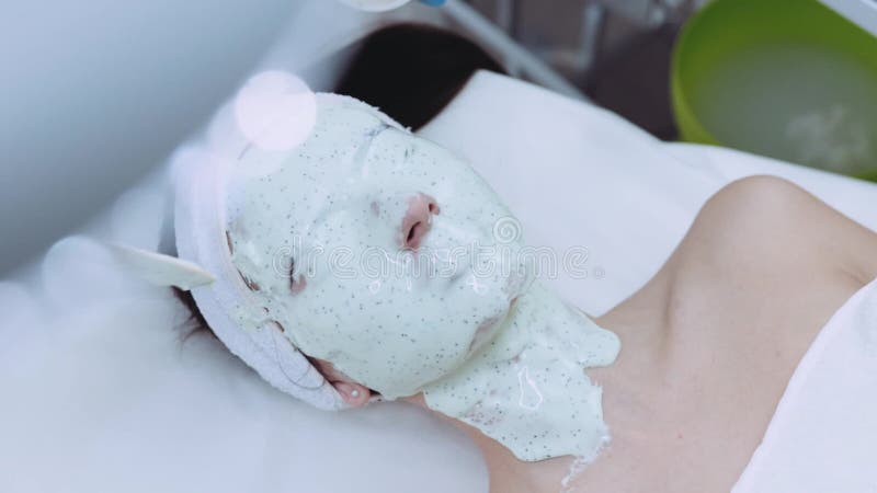 Взгляд вращения женской стороны совершенно предусматриванной с органической маской красоты профессиональным beautician в курорте