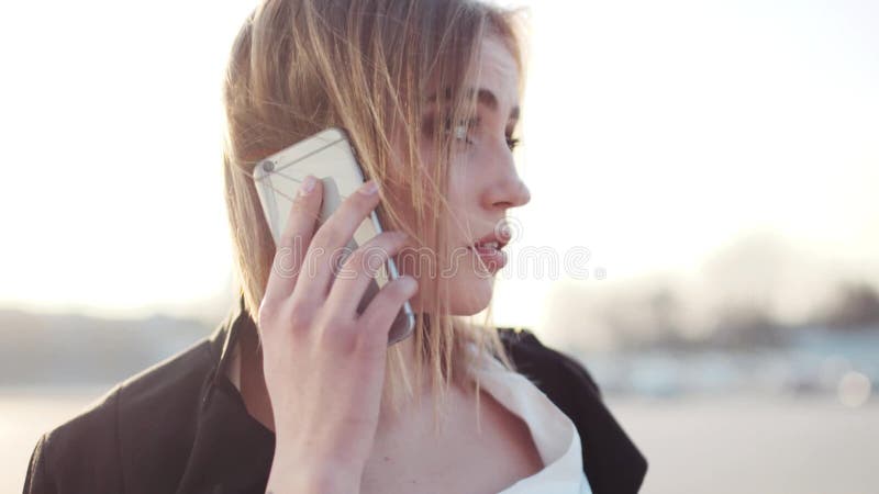Взгляд вращения привлекательной молодой белокурой женщины с естественным составом говоря на ее телефоне Успешная карьера, совреме
