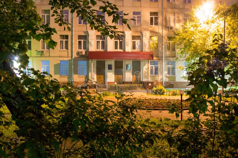 Night view of the school building through the bushes. Night view of the school building through the bushes