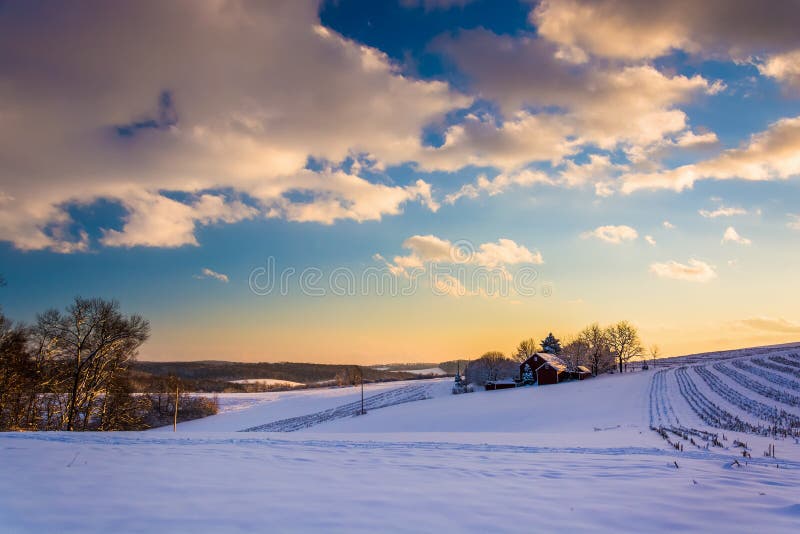 Взгляд снега покрыл поля фермы и Rolling Hills на заходе солнца внутри стоковое фото