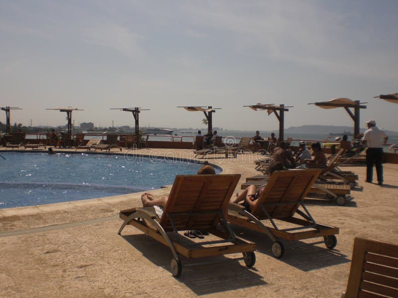 Взгляд бассейна и sunbeds вокруг с купальщиками загорая в гостинице Вест-Инди стоковая фотография rf Взгляд бассейна и sunbeds вокруг с купальщиками загорая в гостинице Вест-Инди стоковая фотография rf