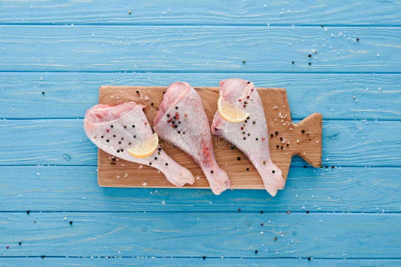 взгляд сверху сырцовых куриных ножек с corns перца и лимона на деревянной доске стоковые изображения взгляд сверху сырцовых куриных ножек с corns перца и лимона на деревянной доске стоковые изображения