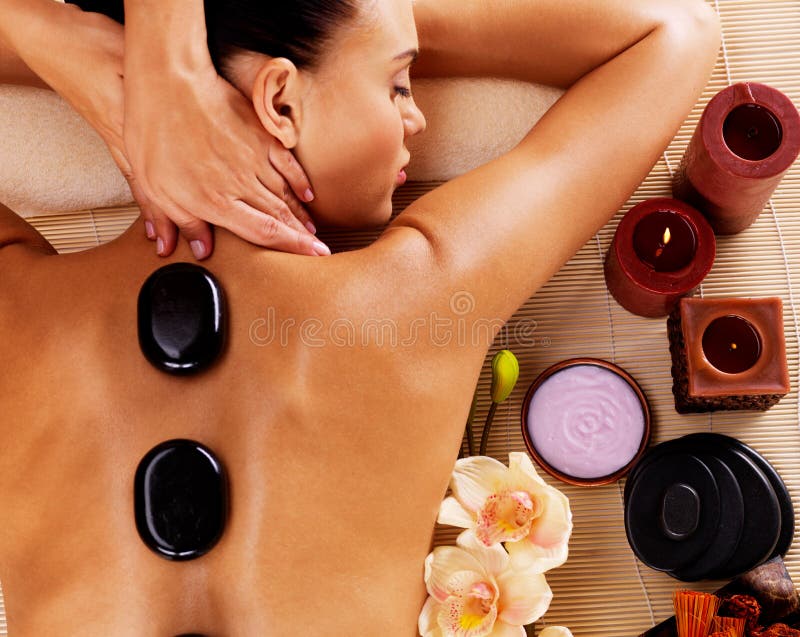 Adult woman having hot stone massage in spa salon. Beauty treatment concept. Adult woman having hot stone massage in spa salon. Beauty treatment concept.