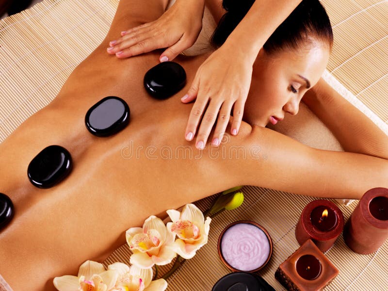 Adult woman having hot stone massage in spa salon. Beauty treatment concept. Adult woman having hot stone massage in spa salon. Beauty treatment concept.