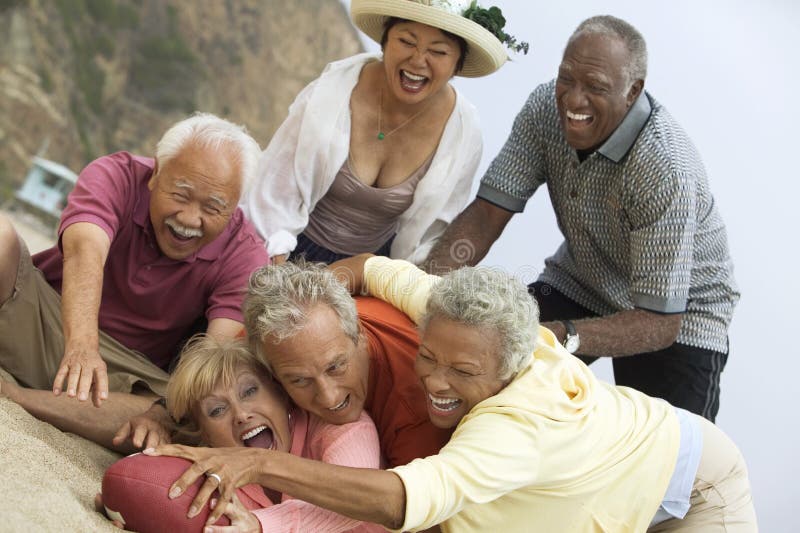 Group of adult multiethnic friends playing American football on the beach. Group of adult multiethnic friends playing American football on the beach