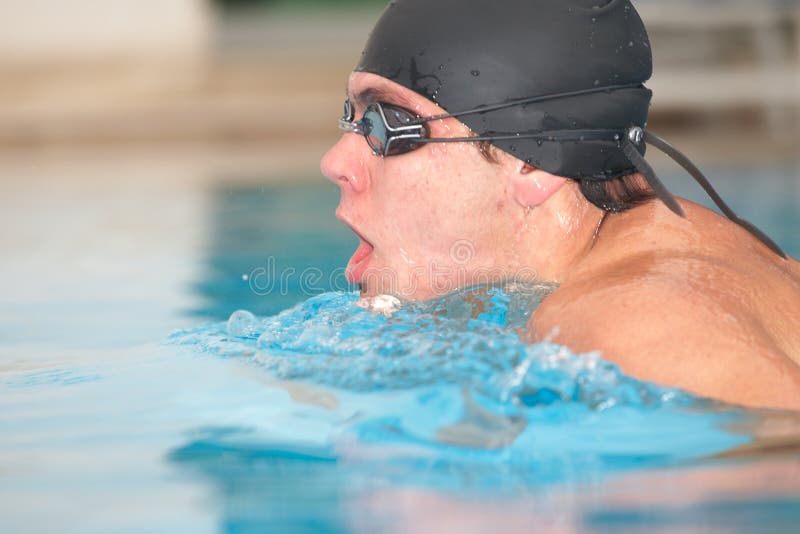 Healthy young adult male aquatic athlete. Professional swimmer in blue water. Healthy young adult male aquatic athlete. Professional swimmer in blue water