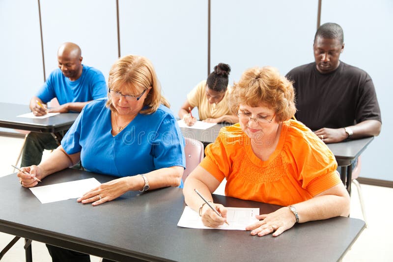 Diverse adult education or college class taking a test. Diverse adult education or college class taking a test.