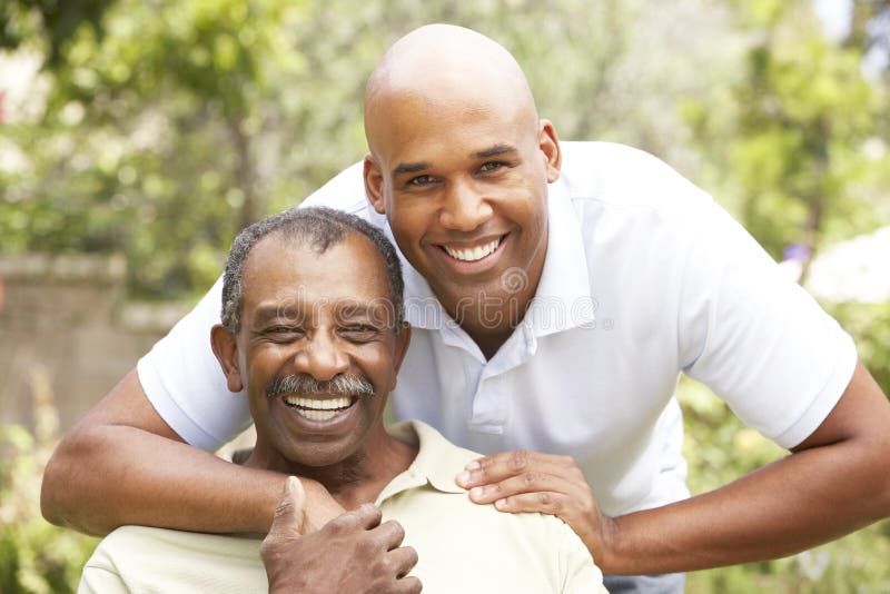 Senior Man Hugging Adult Son In Garden. Senior Man Hugging Adult Son In Garden