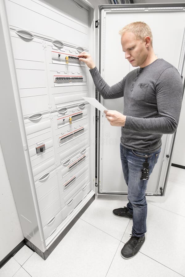 Взрыватель переключателя инженера и читает техническая газета стоковое изображение rf Взрыватель переключателя инженера и читает техническая газета стоковое изображение rf