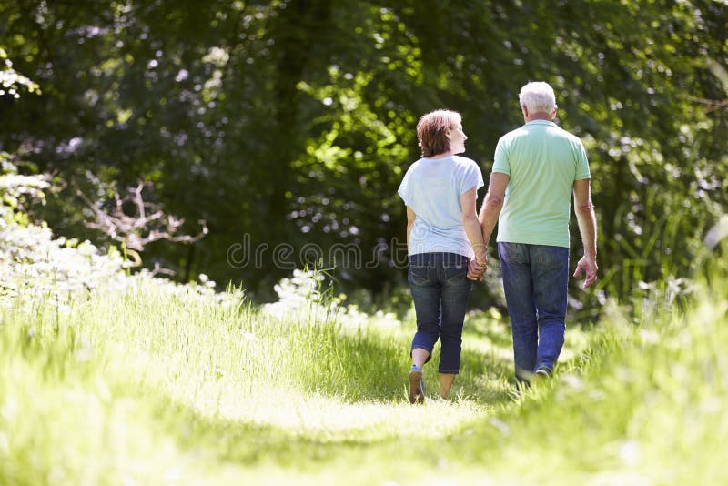 Rear View Of Senior Couple Walking In Summer Countryside. Rear View Of Senior Couple Walking In Summer Countryside