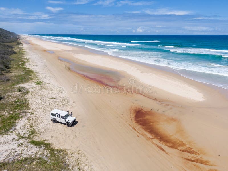 High angle aerial drone view of a four-wheel drive off-road vehicle standing on Seventy Five Mile Beach on Fraser Island, Queensland, Australia. Fraser Island is popular for locals and tourists. High angle aerial drone view of a four-wheel drive off-road vehicle standing on Seventy Five Mile Beach on Fraser Island, Queensland, Australia. Fraser Island is popular for locals and tourists.