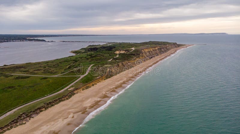 Вид с воздуха головы Hengistbury с величественным песчаным пляжем, кристаллической зеленой воды, травянистым холмом, огромной ска стоковое изображение rf
