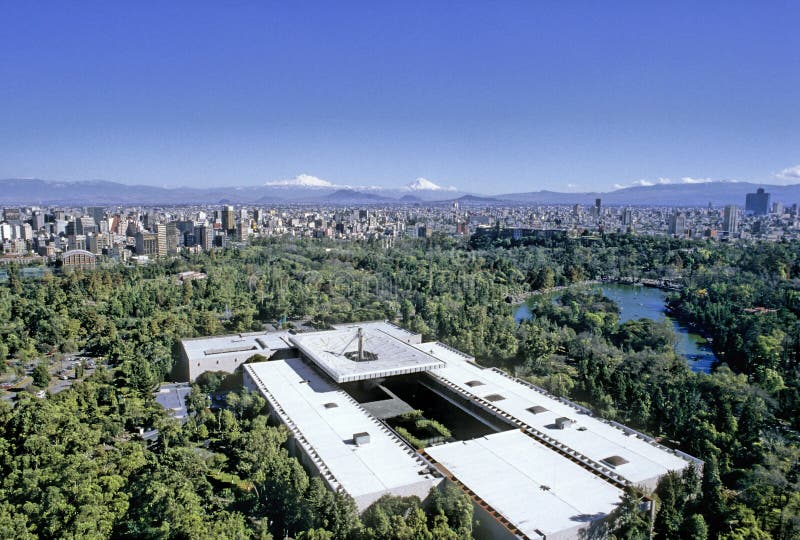 Aerial view of Mexico City on a clear day without contamination. In the foreground the National Museum of Anthropology surrounded by Chapultepec Park, buildings and skyscrapers in the middle distance, snowed volcanoes on the horizon. Aerial view of Mexico City on a clear day without contamination. In the foreground the National Museum of Anthropology surrounded by Chapultepec Park, buildings and skyscrapers in the middle distance, snowed volcanoes on the horizon