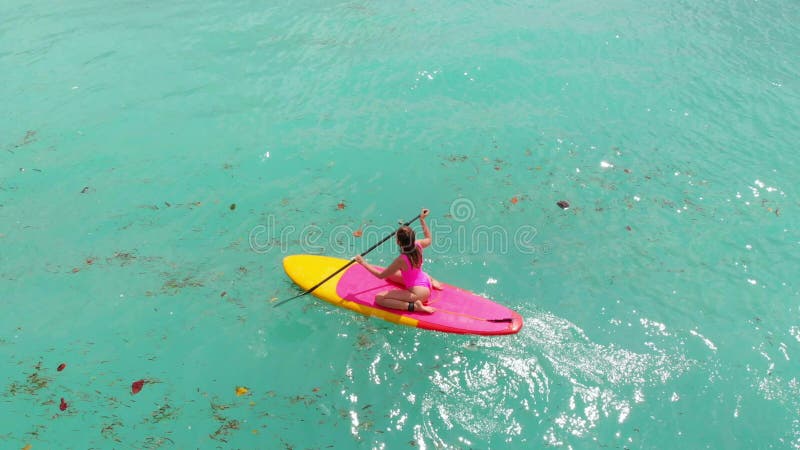 Вид с воздуха на женщину на доске в голубом океане