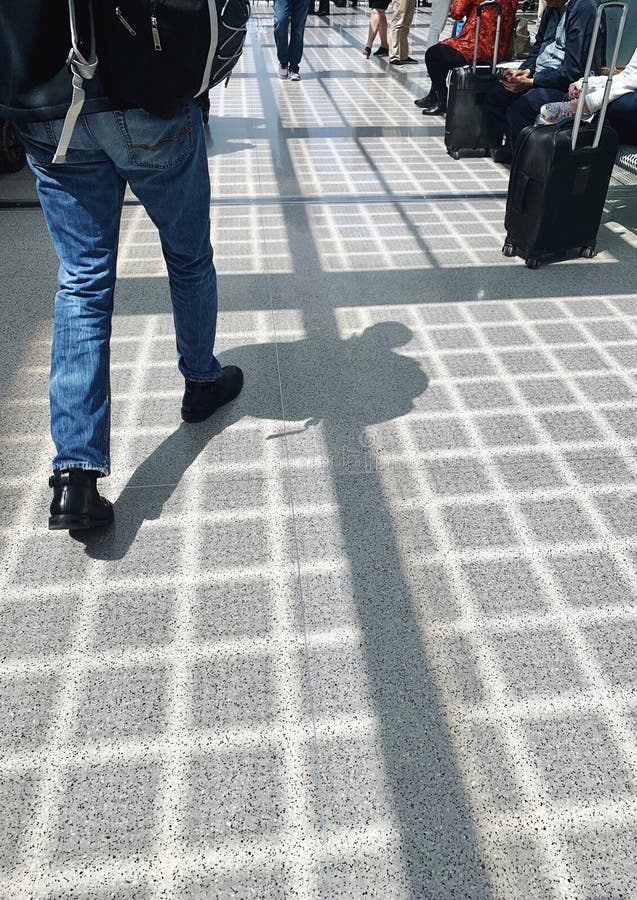 Вид сзади нижней части человека в джинсах идя внутри аэропорта стоковые изображения Вид сзади нижней части человека в джинсах идя внутри аэропорта стоковые изображения