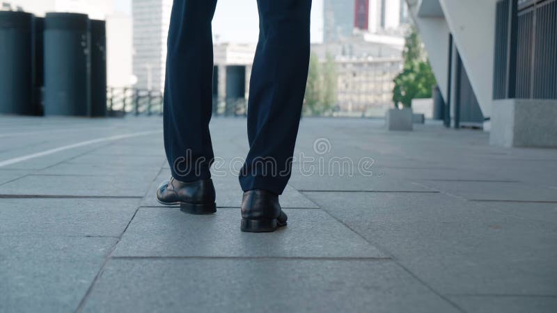 вид сзади ноги бизнесмена коммутирующих на работу. уверенный мужчина в кожаных туфлях и официальном костюме гуляет по центру город
