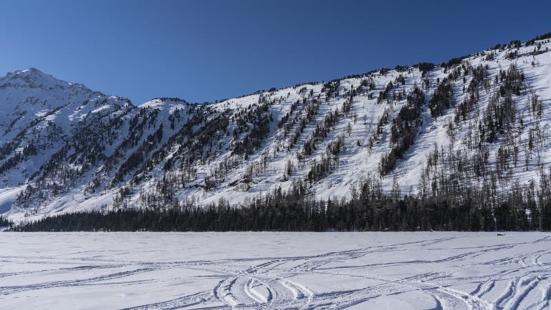 видны следы шин и снегоходов на поверхности снежного покрова замороженных озер.